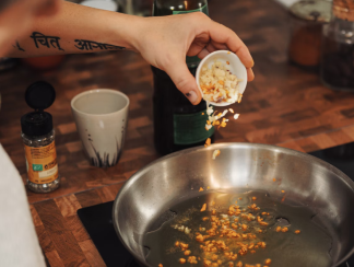 chef sprinkling chopped garlic into hot pan