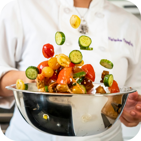 Chef tossing vegetables in bowl