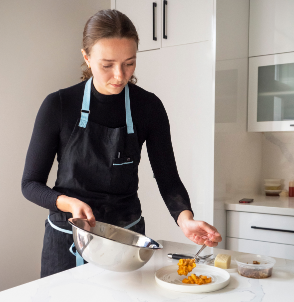 Woman adding green vegetable to boiling pot of water.